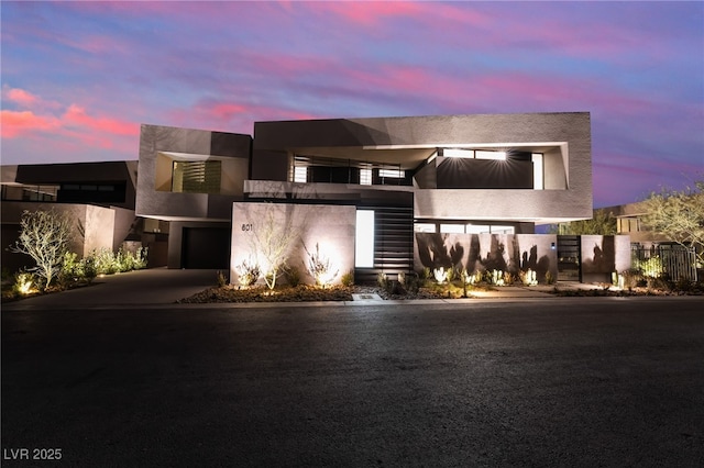 contemporary house featuring concrete driveway, an attached garage, fence, and stucco siding