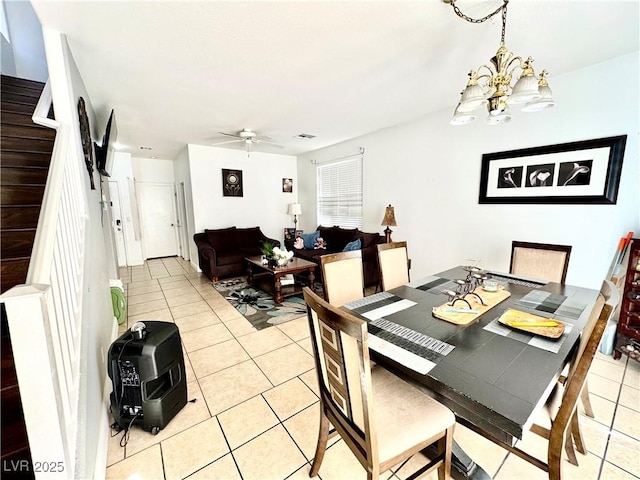 dining area featuring heating unit, visible vents, stairway, light tile patterned flooring, and ceiling fan with notable chandelier