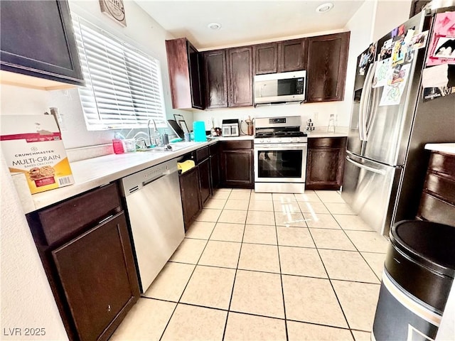 kitchen with light countertops, appliances with stainless steel finishes, light tile patterned flooring, and a sink