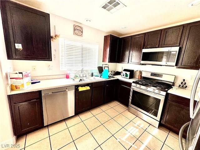 kitchen featuring dark brown cabinetry, a sink, visible vents, light countertops, and appliances with stainless steel finishes