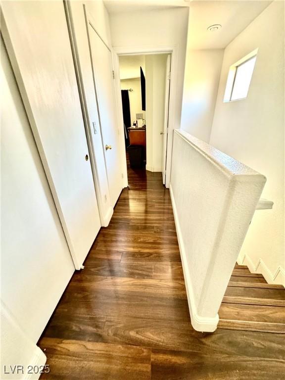 corridor with dark wood finished floors and baseboards