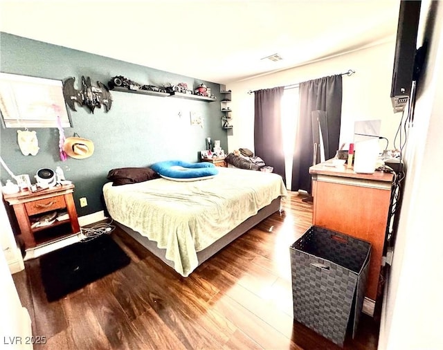 bedroom featuring baseboards, visible vents, and wood finished floors