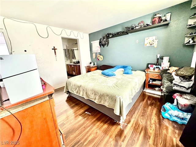 bedroom featuring wood finished floors and connected bathroom