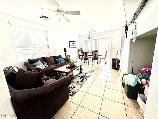 living room with ceiling fan with notable chandelier, visible vents, and light tile patterned floors