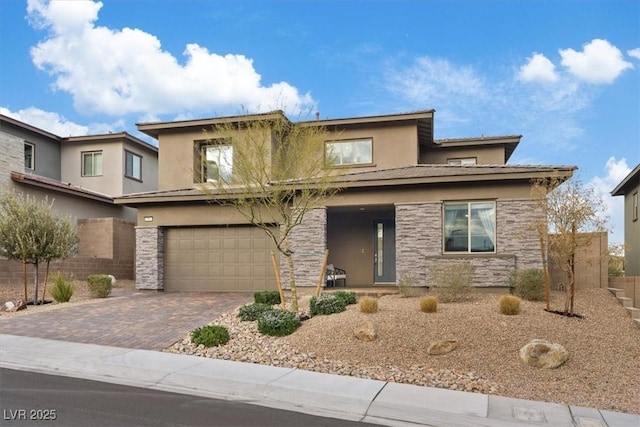 prairie-style house featuring a garage, stone siding, decorative driveway, and stucco siding