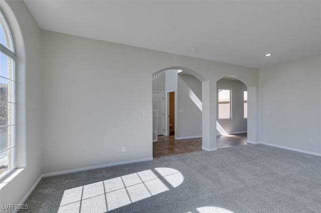 carpeted spare room featuring arched walkways, recessed lighting, and baseboards