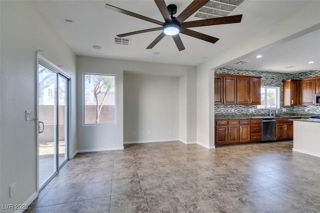 kitchen featuring tasteful backsplash, visible vents, appliances with stainless steel finishes, brown cabinetry, and a sink