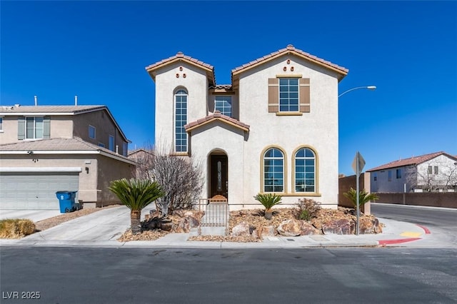 mediterranean / spanish home featuring a garage, concrete driveway, a tile roof, and stucco siding