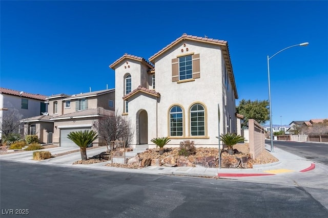 mediterranean / spanish-style home with a garage, a tile roof, driveway, a residential view, and stucco siding