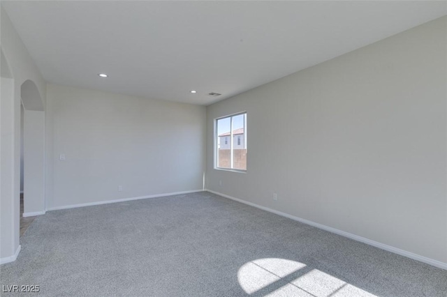 unfurnished room with arched walkways, recessed lighting, light colored carpet, and baseboards