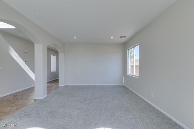 empty room with arched walkways, carpet, baseboards, and recessed lighting