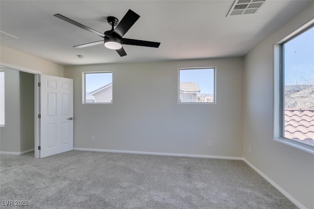 spare room featuring light carpet, a ceiling fan, visible vents, and baseboards