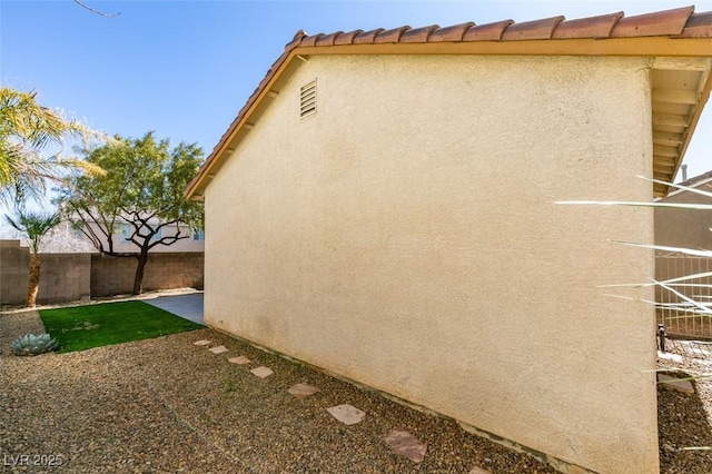 view of side of home with fence and stucco siding