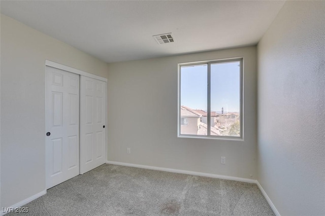 unfurnished bedroom featuring a closet, carpet flooring, visible vents, and baseboards