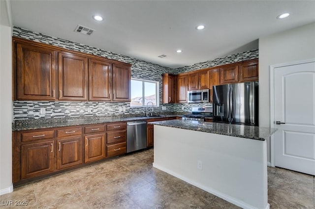 kitchen featuring visible vents, appliances with stainless steel finishes, dark stone counters, and a center island