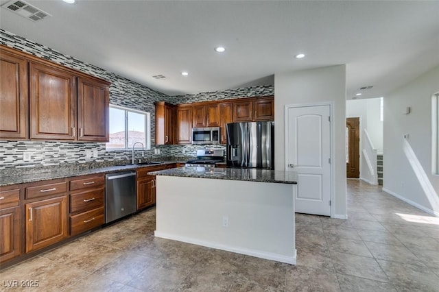 kitchen with visible vents, decorative backsplash, dark stone counters, a kitchen island, and stainless steel appliances