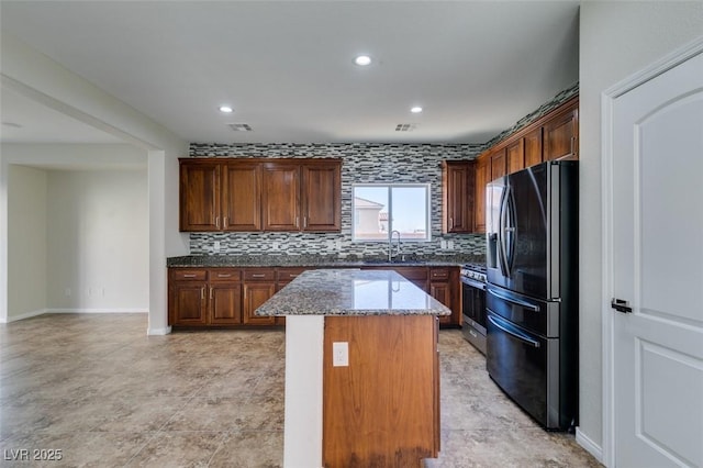 kitchen with stone counters, tasteful backsplash, stainless steel appliances, and a center island