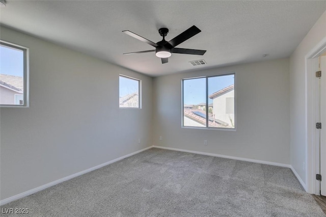 empty room with carpet floors, a ceiling fan, and baseboards