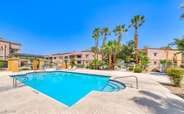 pool with a patio, fence, and a residential view