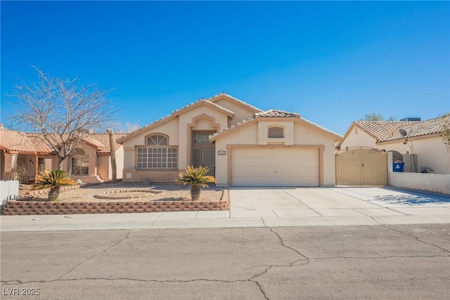 mediterranean / spanish-style house with stucco siding, concrete driveway, a gate, a garage, and a tiled roof