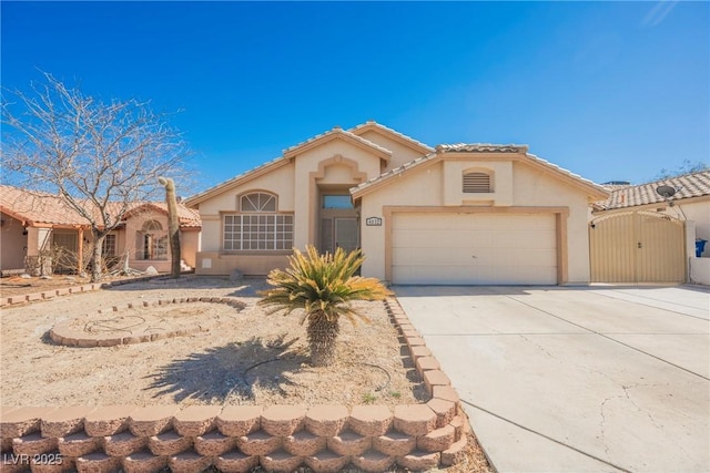 mediterranean / spanish-style house featuring a tile roof, stucco siding, concrete driveway, an attached garage, and a gate