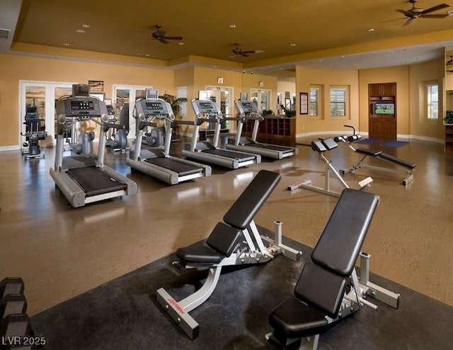 exercise room with ceiling fan, baseboards, and a tray ceiling