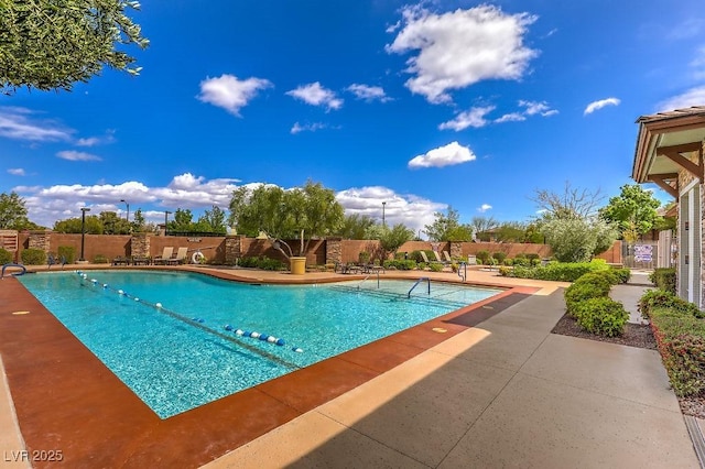 pool with a patio area and fence