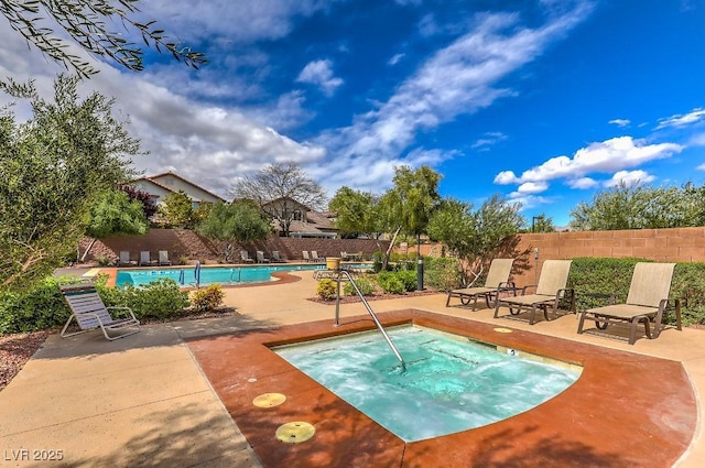 pool with a patio, a fenced backyard, and a hot tub