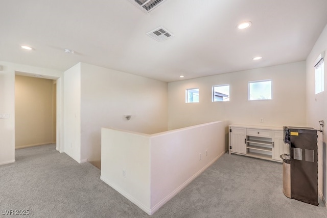 corridor featuring a wealth of natural light, light colored carpet, and visible vents