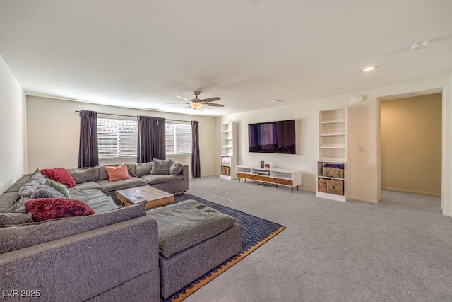 carpeted living room featuring ceiling fan, built in shelves, and baseboards