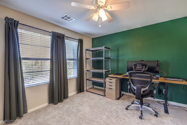 home office featuring light carpet, ceiling fan, visible vents, and baseboards