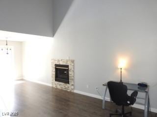 home office featuring a towering ceiling, a fireplace, baseboards, and dark wood-type flooring