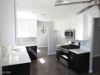 kitchen with dark wood-type flooring, white cabinetry, stainless steel appliances, and light countertops