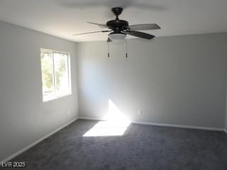 unfurnished room featuring baseboards, dark carpet, and a ceiling fan