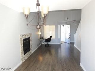 unfurnished office featuring dark wood finished floors, a notable chandelier, a fireplace, and baseboards