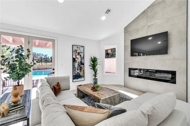 living area featuring visible vents, lofted ceiling, wood finished floors, a fireplace, and recessed lighting