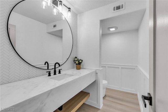 bathroom with toilet, visible vents, wood finished floors, and vanity