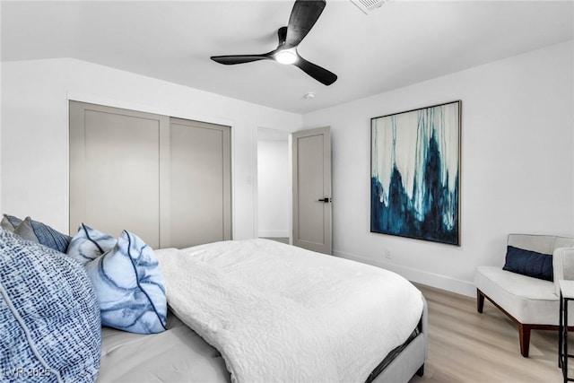 bedroom with light wood finished floors, baseboards, a ceiling fan, and a closet