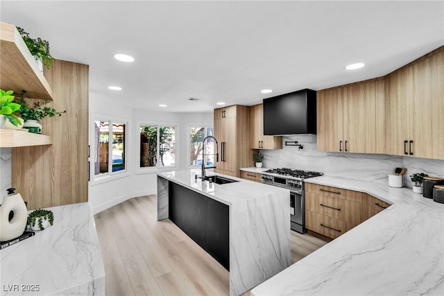 kitchen featuring high end stove, a sink, open shelves, an island with sink, and modern cabinets