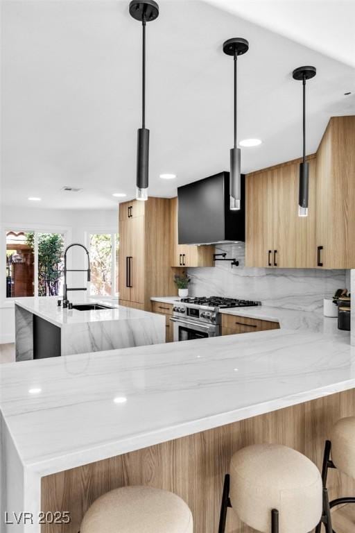 kitchen with high end stove, a sink, a kitchen breakfast bar, hanging light fixtures, and modern cabinets