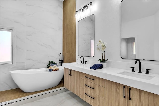 bathroom with a freestanding bath, marble finish floor, double vanity, and a sink