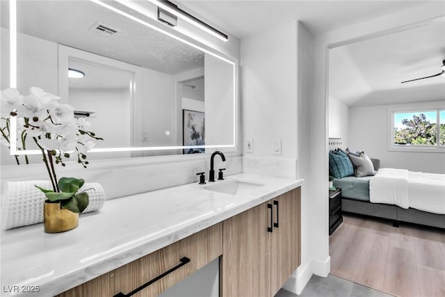 ensuite bathroom with visible vents, wood finished floors, connected bathroom, and vanity