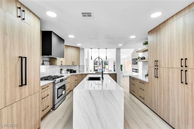 kitchen with modern cabinets, stainless steel stove, a center island with sink, and open shelves