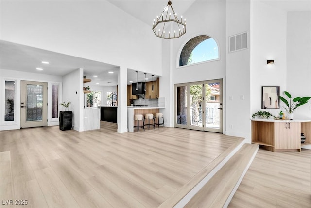 living room featuring light wood-type flooring, visible vents, a notable chandelier, and recessed lighting