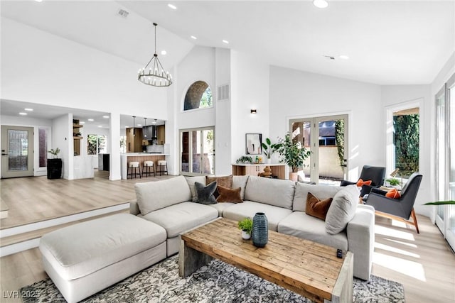 living area with light wood finished floors, visible vents, a chandelier, and french doors