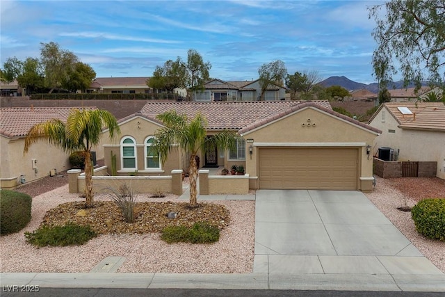 mediterranean / spanish-style home featuring stucco siding, a garage, driveway, and a tiled roof