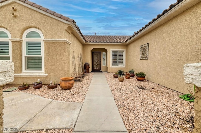 doorway to property with a tile roof and stucco siding