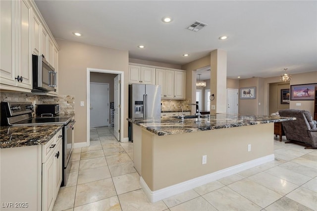 kitchen featuring visible vents, dark stone countertops, open floor plan, appliances with stainless steel finishes, and an inviting chandelier