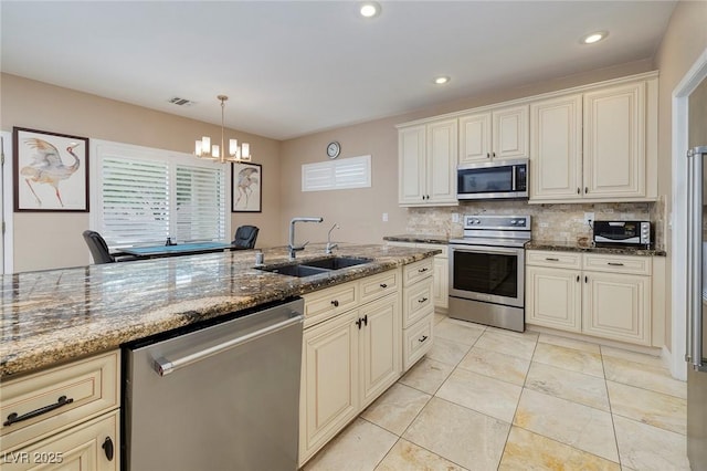 kitchen featuring visible vents, dark stone counters, a sink, decorative backsplash, and appliances with stainless steel finishes