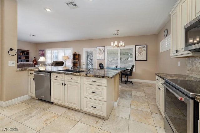 kitchen with visible vents, backsplash, dark stone countertops, cream cabinetry, and stainless steel appliances